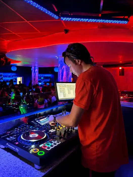 DJ alla consolle della discoteca Kalymnos, con luci rosse e blu sulla pista