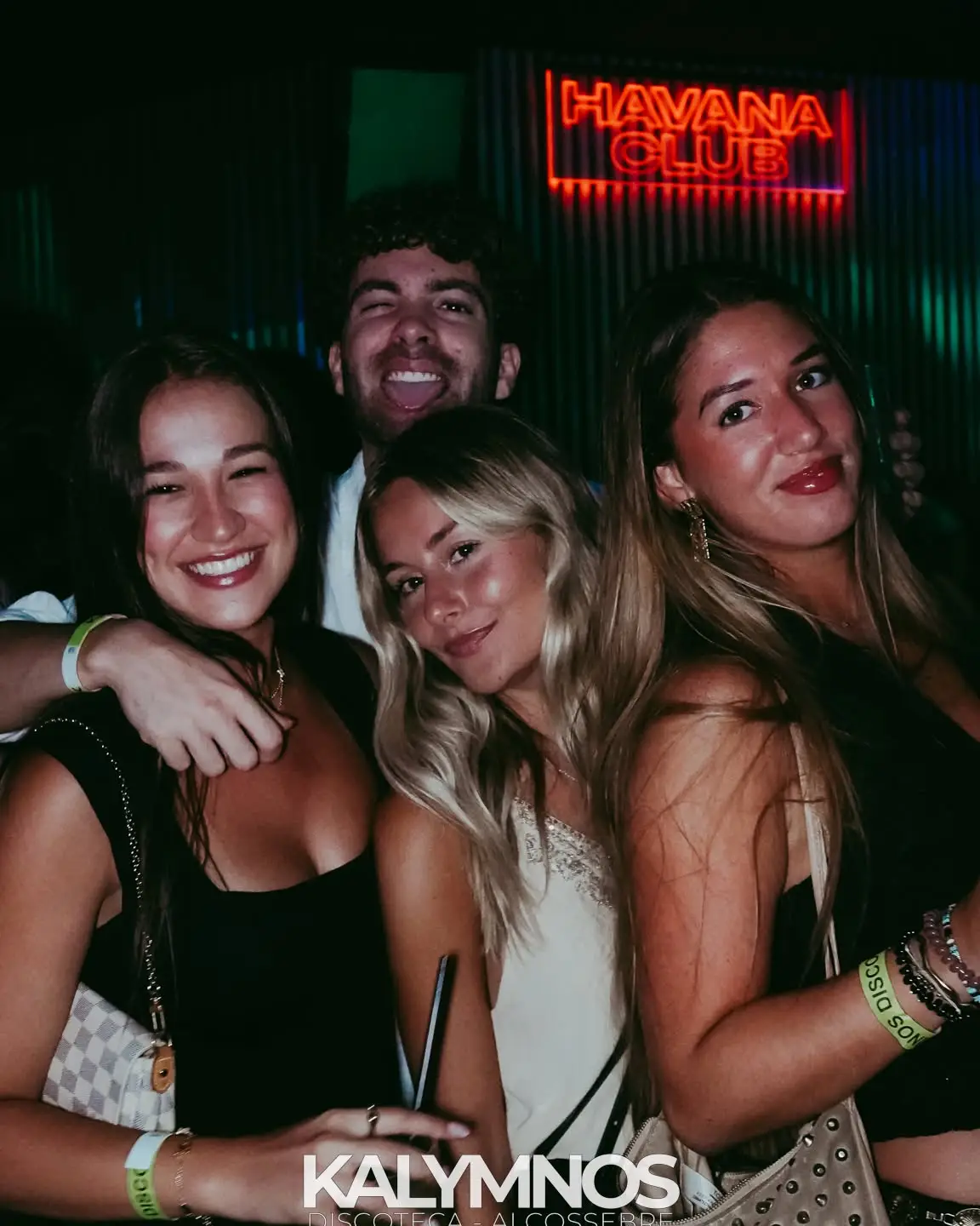 Amiche al bancone del Kalymnos sotto l'insegna al neon di Havana Club